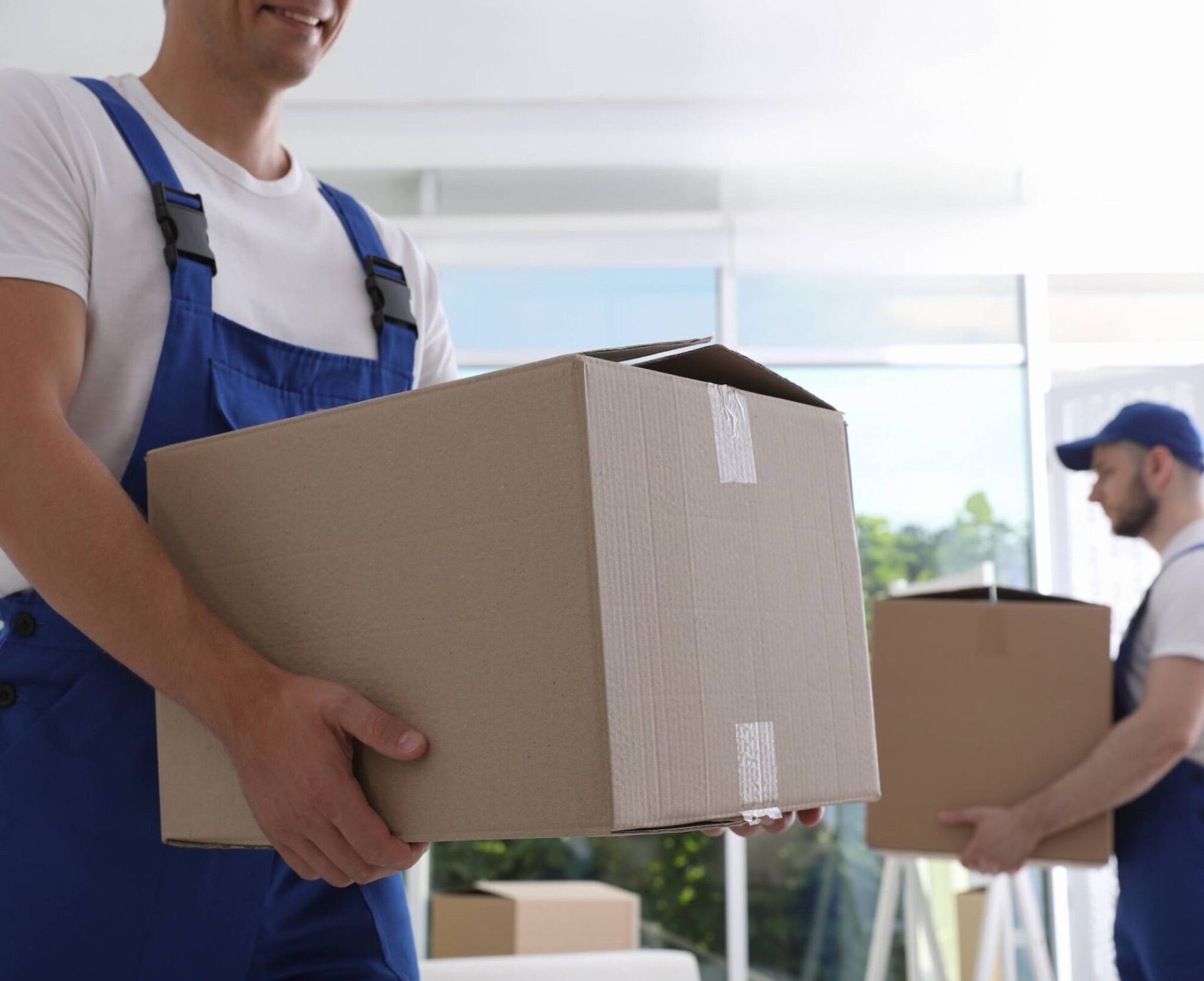 Moving service employees with cardboard boxes in room, closeup